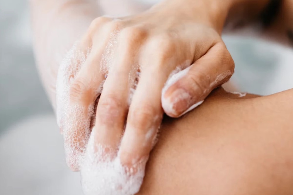 Persona enjabon&aacute;ndose el brazo en la ducha. La foto es ilustrativa.